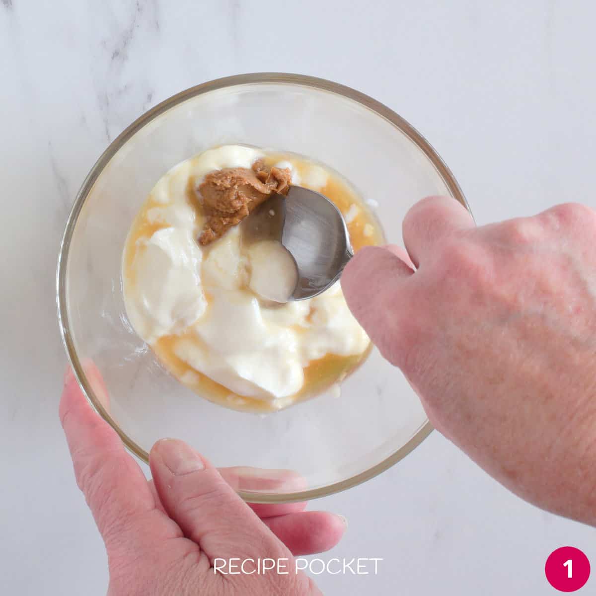 Mixing biscoff spread, and yogurt in a glass bowl.