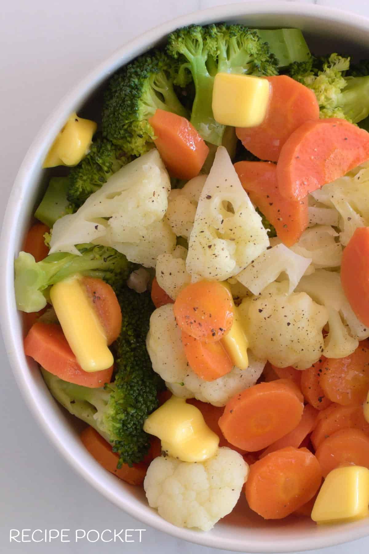 A close up of vegetables with butter pieces on top.