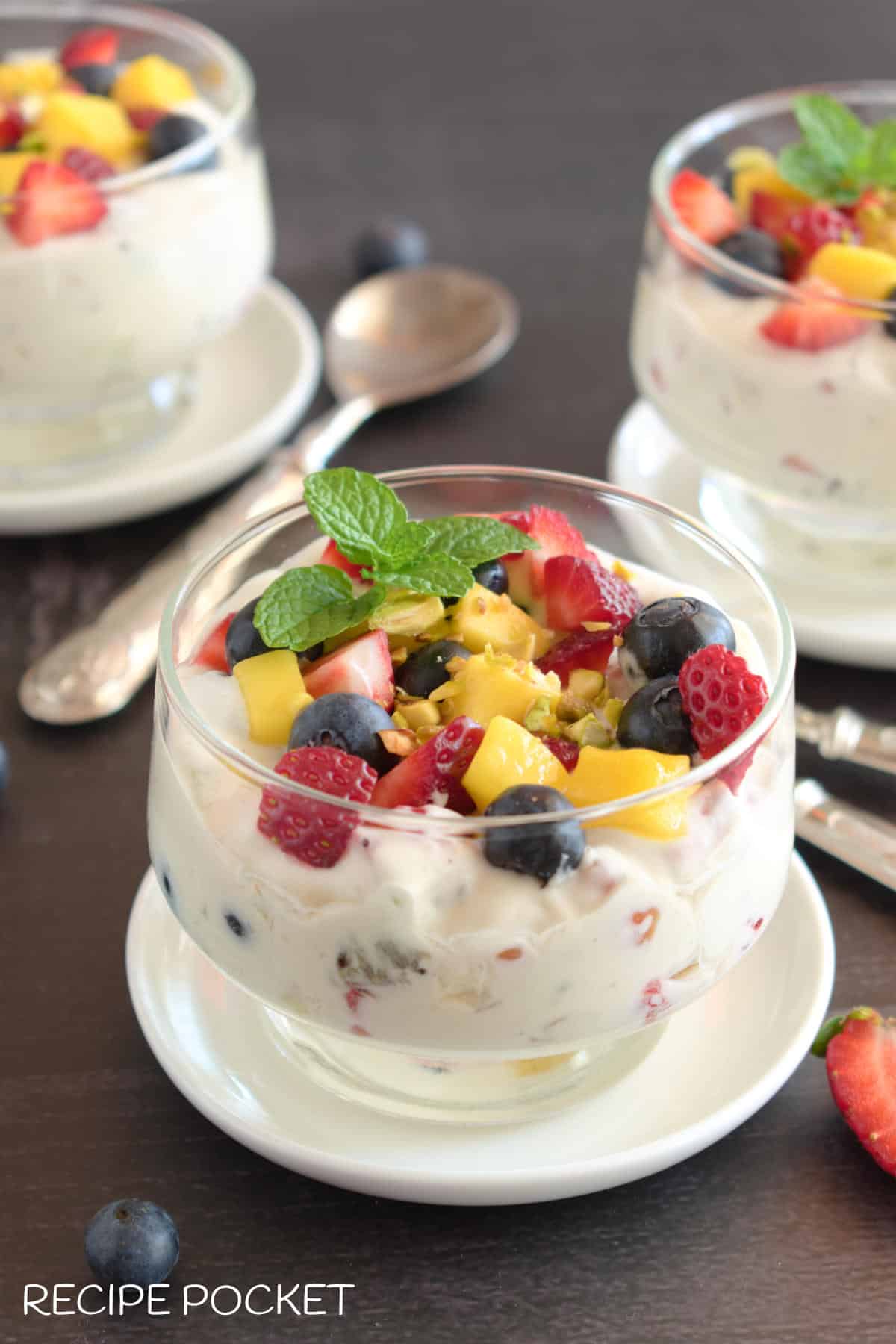Three servings of a cream dessert with fruit on top.