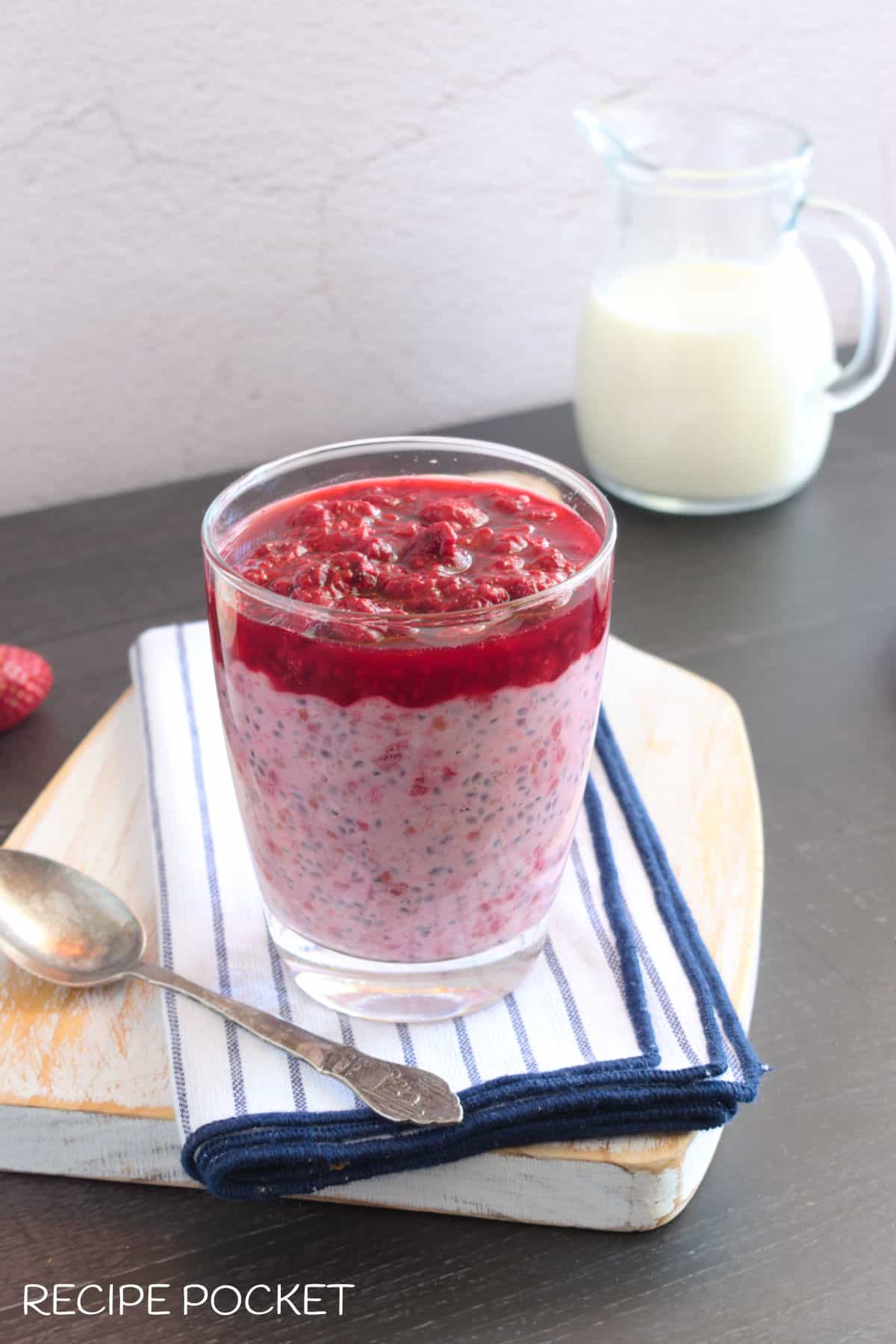 Photo showing a thick layer of raspberry sauce on top of raspberry overnight oats in a glass.