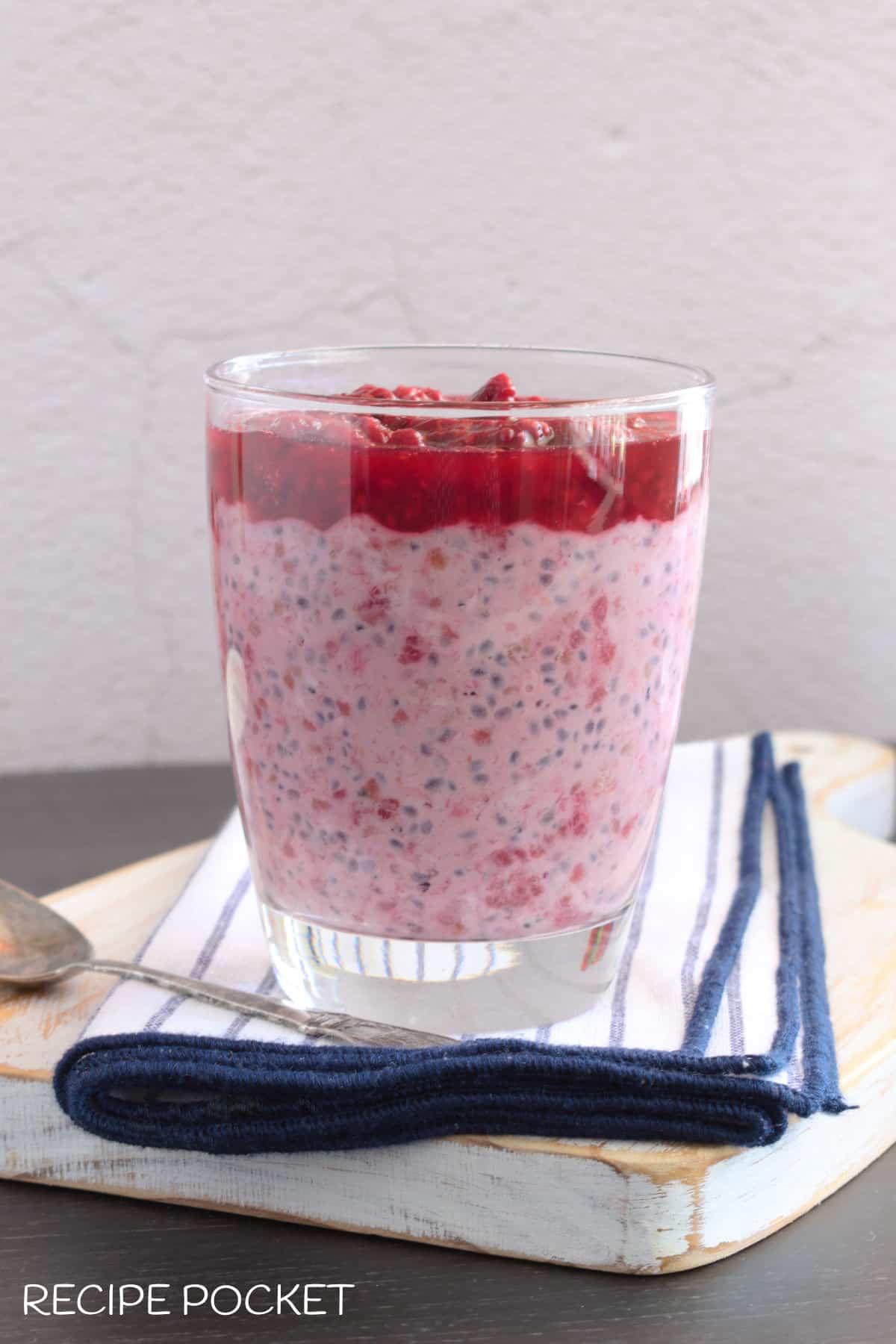 Pink colored raspberry overnight oats in a glass.