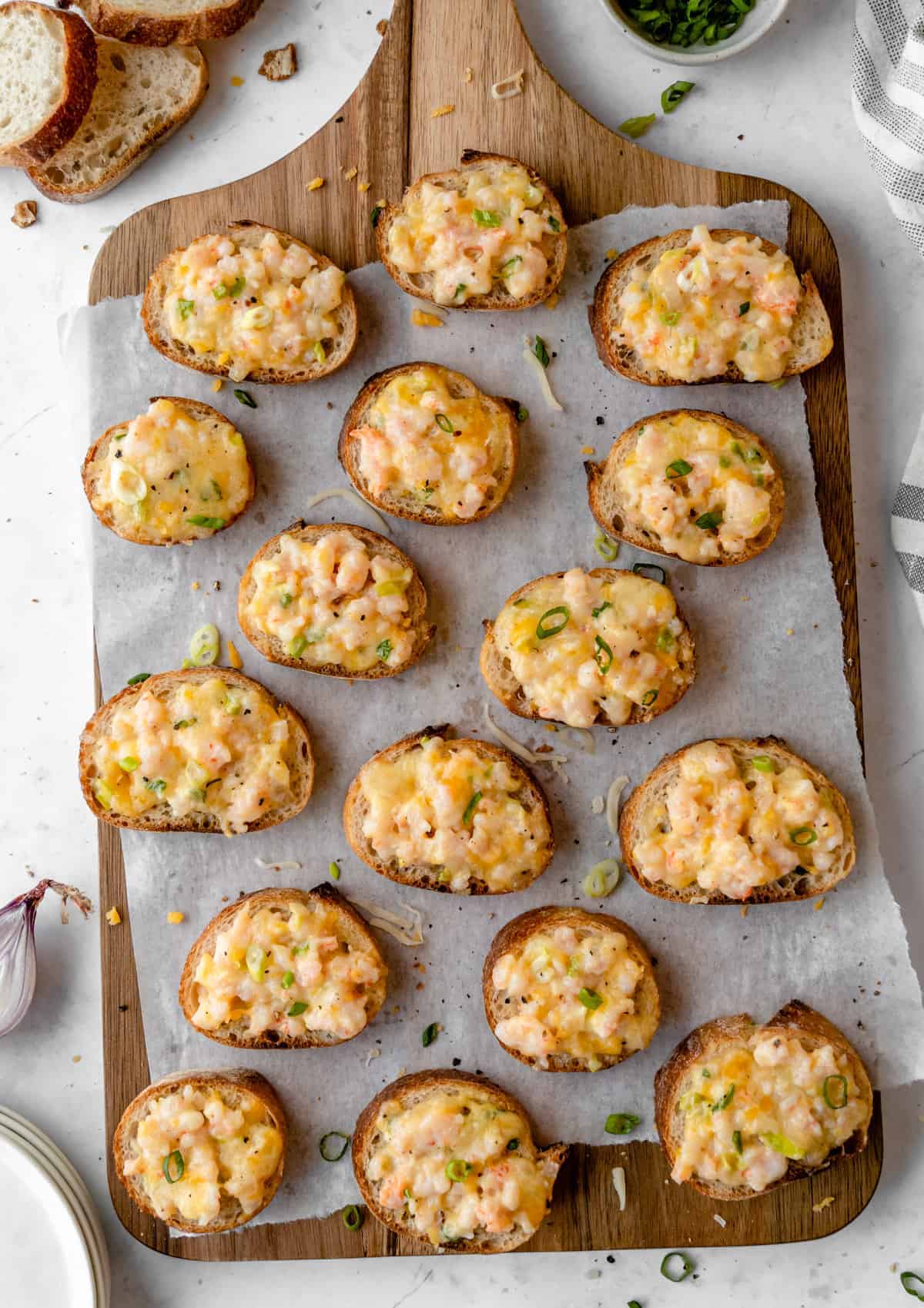 Shrimp on toast appetizers on a wooden board.