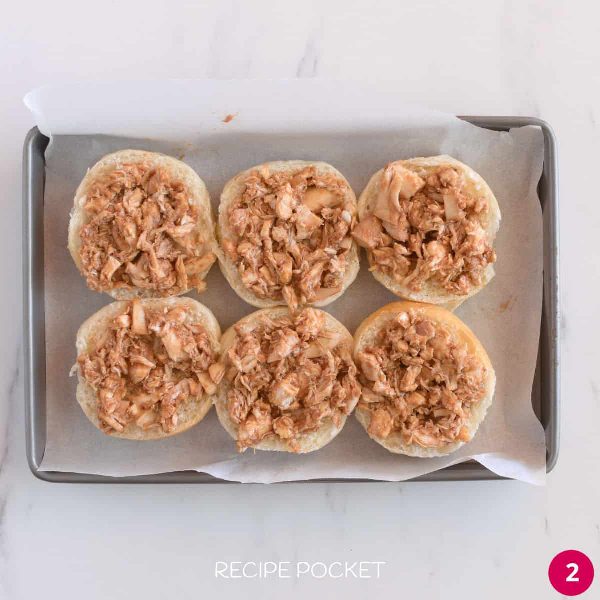 Slider buns with chicken coated in bbq sauce.