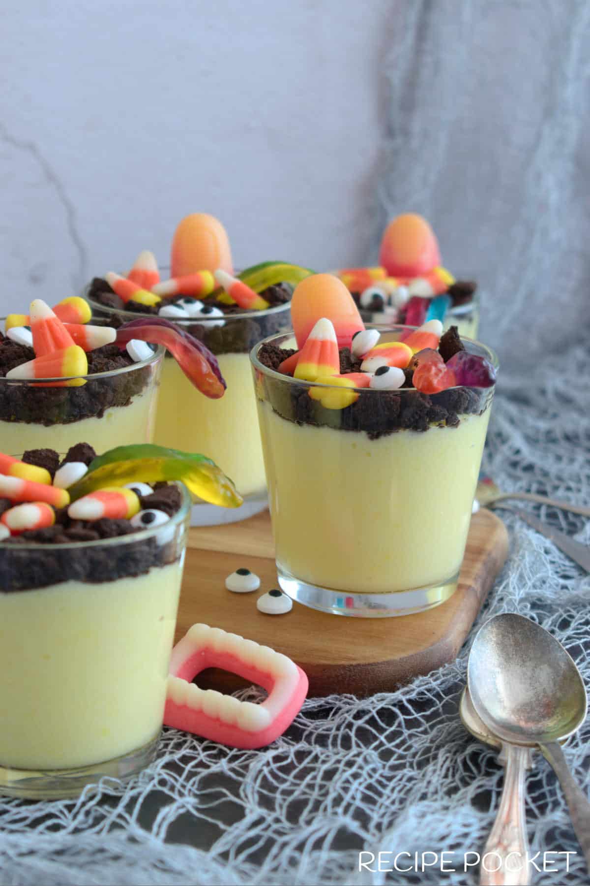 Pudding cups on display on a table decorated in a loosely woven cloth.