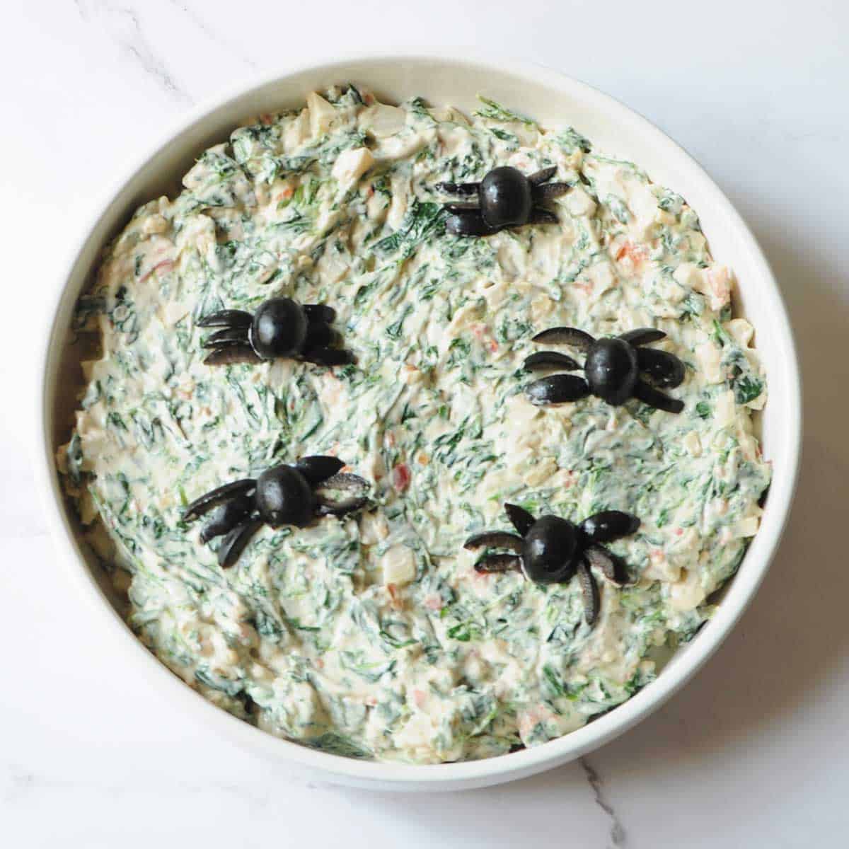 Halloween spinach dip with black olive spiders.