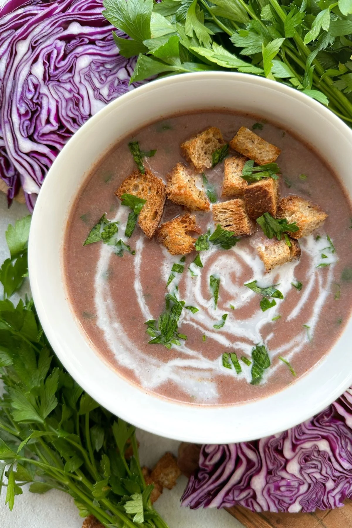 A bowl of purple cabbage soup with croutons.