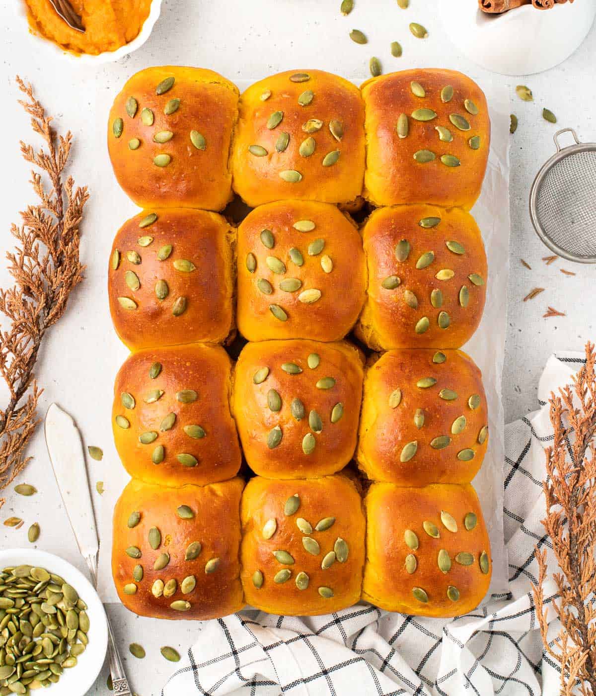 One dozen pumpkin buns with pumpkin seed topping.