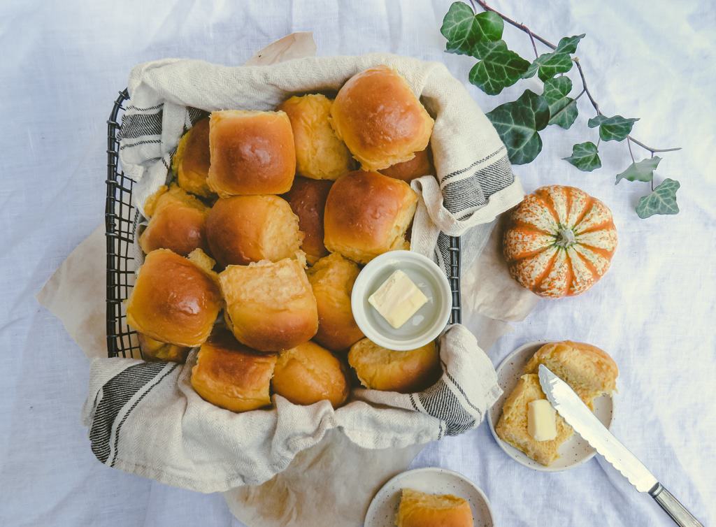 A pile of butternut dinner rolls on a cake rack.
