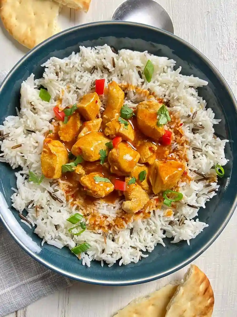 Butter chicken and rice in a blue bowl.