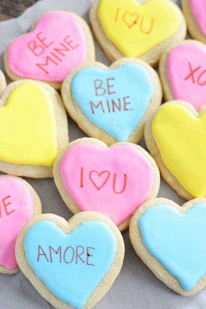 Conversation heart cookies in pink, yellow and blue.
