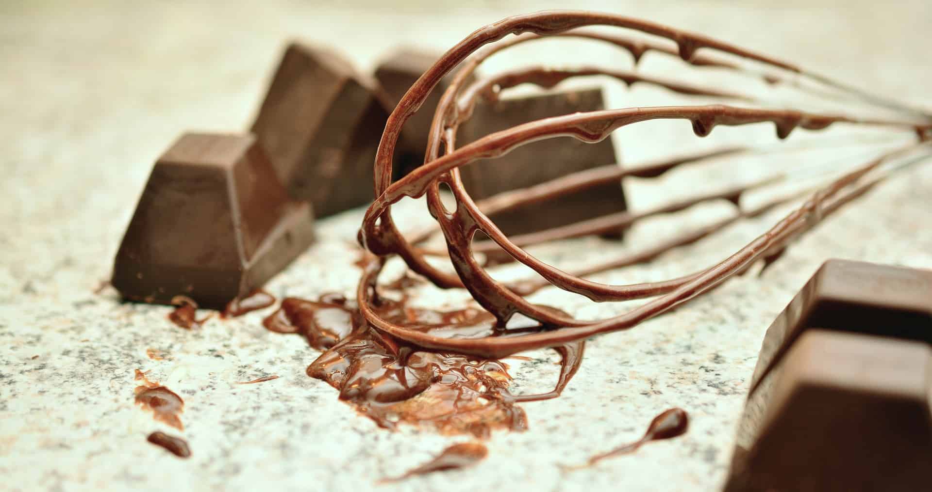 A whisk with melted chocolate on it.
