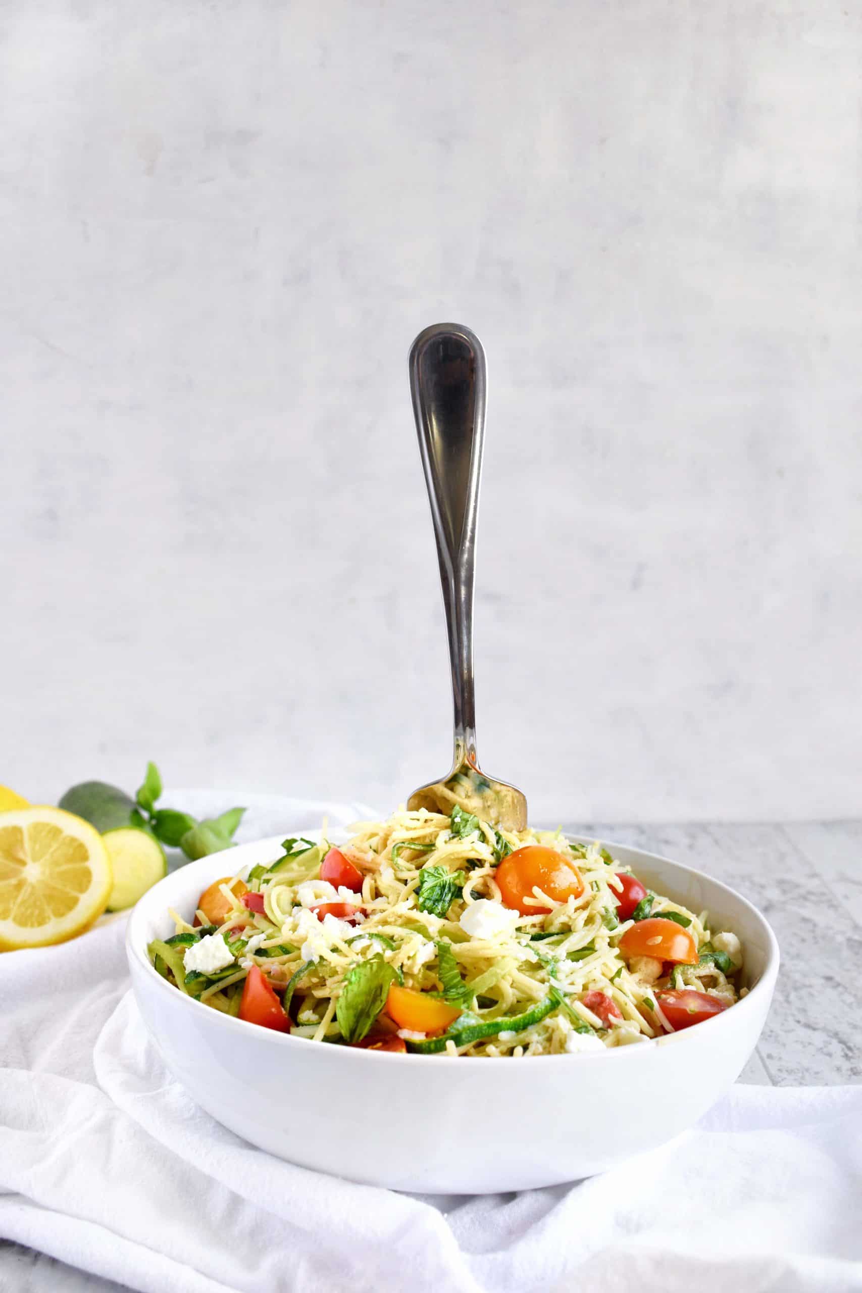 A bowl with pasta with a fork standing up in it.