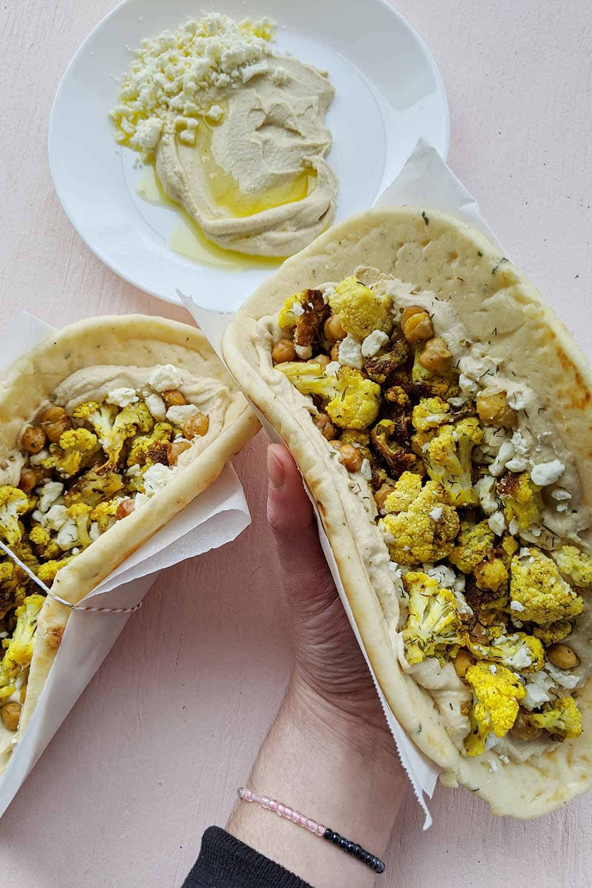 A top down view of a hand holding a veggie wrap made with naan bread.