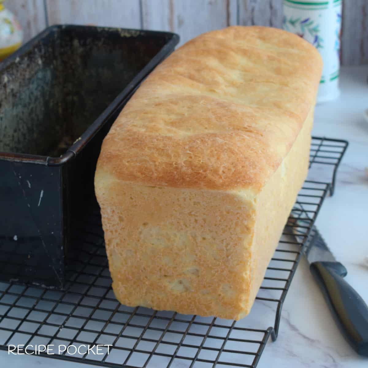A loaf of homemade white bread on a cake rack.