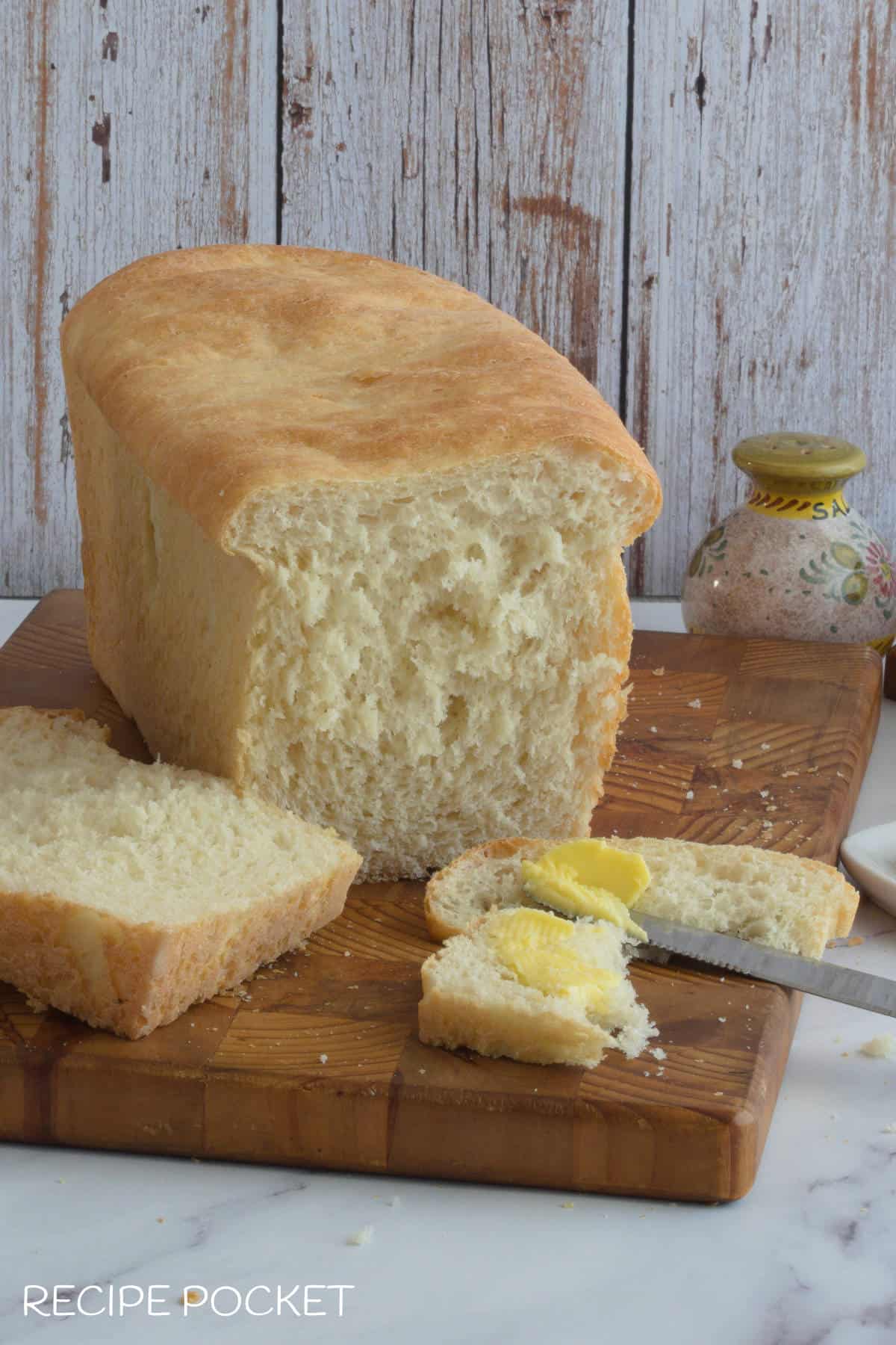A loaf of white bread sliced with butter.
