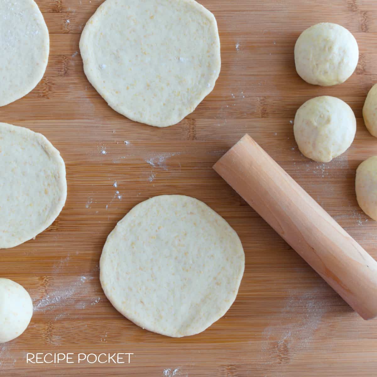 Pita bread dough divided and shaped into balls and rolled into discs.