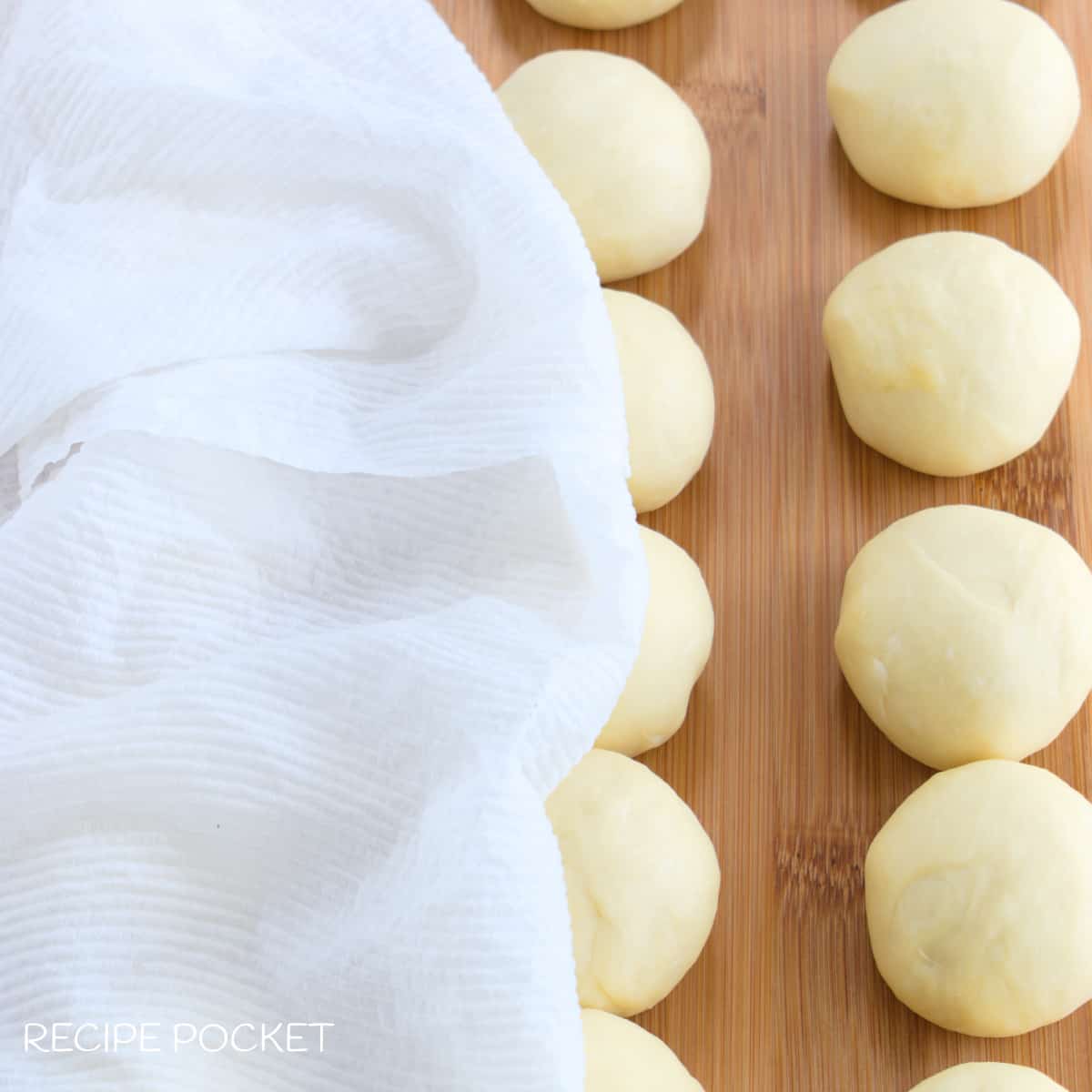 Balls of dough under a damp cloth.