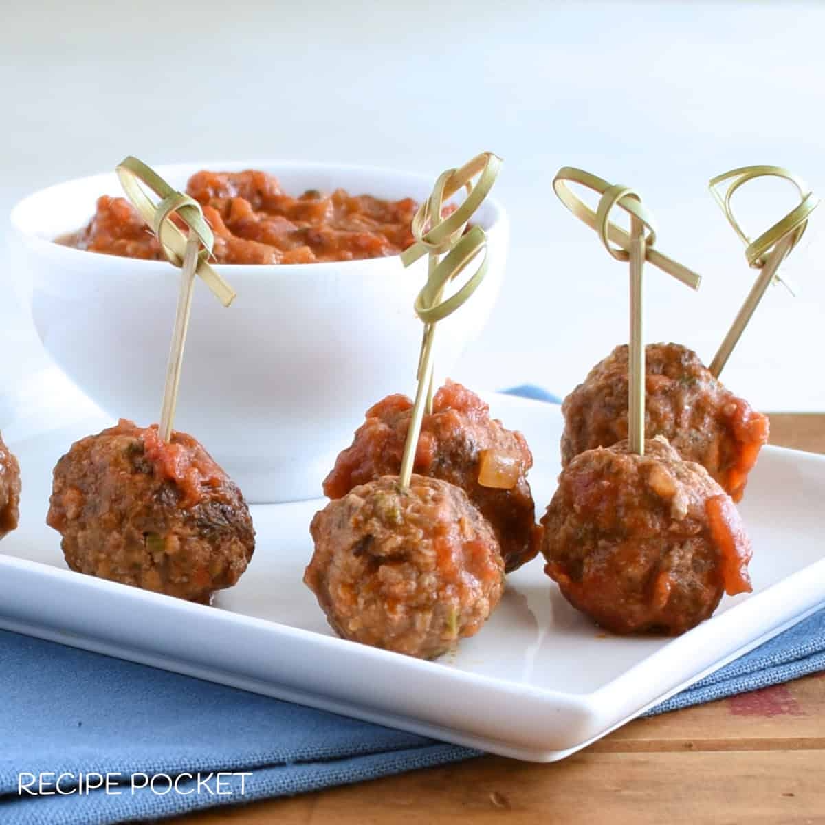 Meatballs on skewers on a white plate.